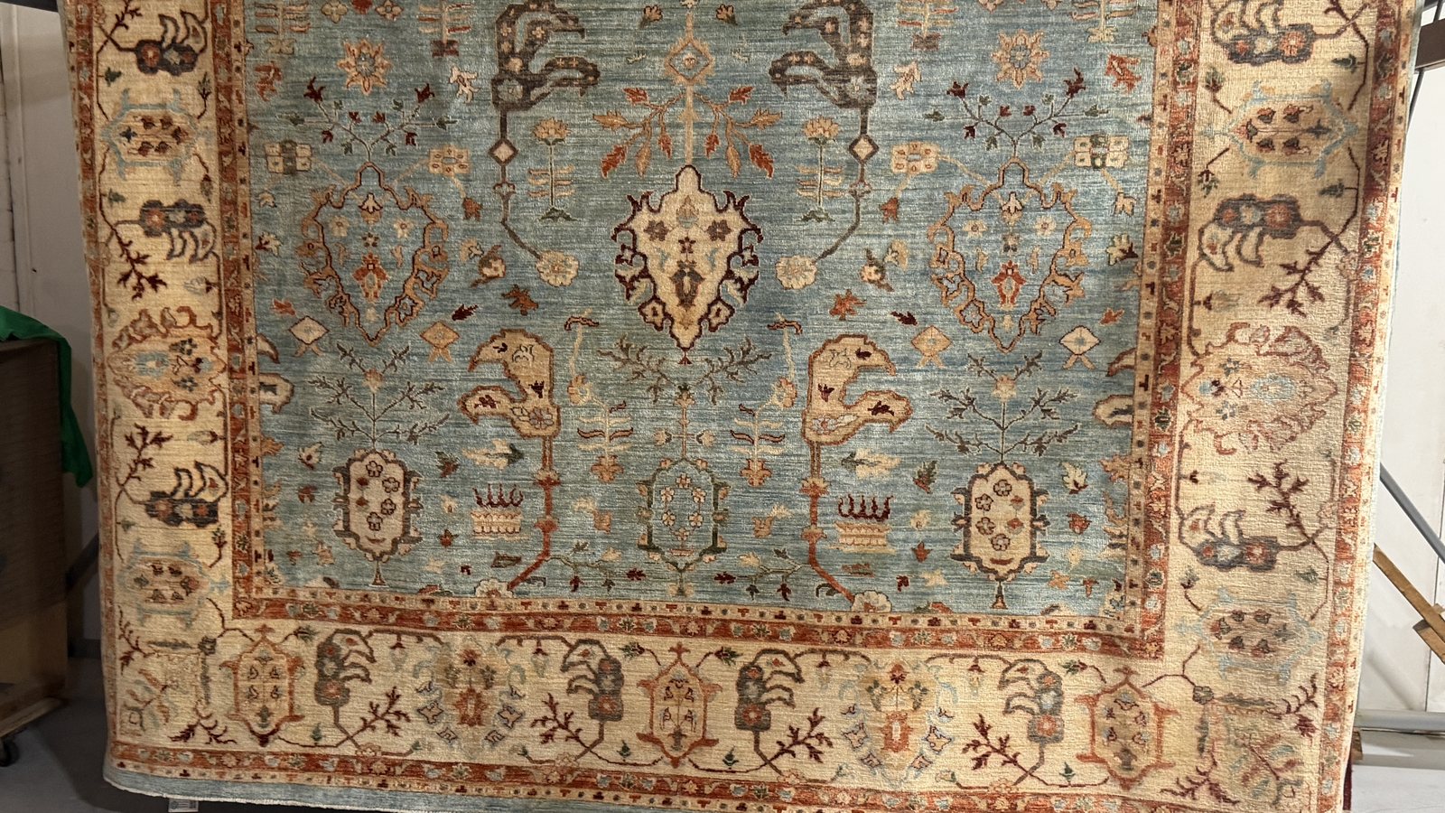 A rug hanging on the drying rack after washing, daylight showing through the weave
